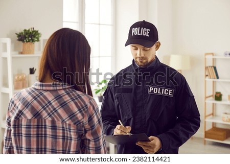 Professional policeman interrogates witness, victim or suspect of crime. Officer working on burglary, felony or murder case, asking young woman questions and taking notes. Police investigation concept Royalty-Free Stock Photo #2382114421