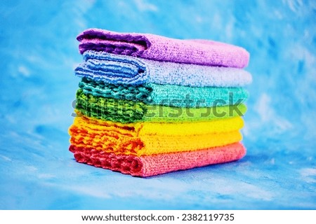 seven bright colored cleaning rags lying on top of each other for upcoming cleansing on a blue background close-up Royalty-Free Stock Photo #2382119735