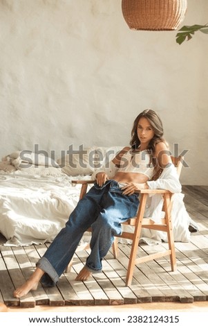 Woman in white shirt and jeans posing interior