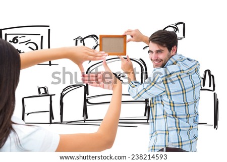 Happy young couple putting up picture frame against living room sketch