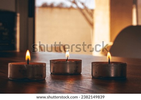 Burning candles placed against window with curtain during aromatherapy session at home