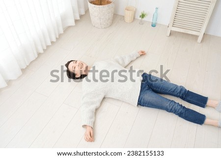 Asian middle aged woman lounging on the living room floor