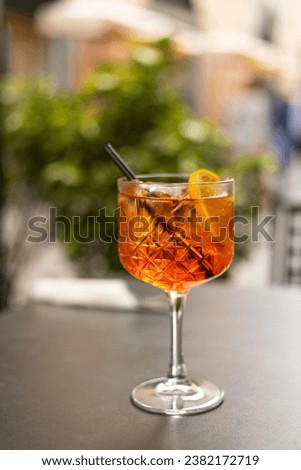 Aperol Spritz Cocktail. Alcoholic beverage based on table with ice cubes and oranges outdoors. Served cocktail with orange slice and straw placed on the table of sidewalk cafe in Italy Royalty-Free Stock Photo #2382172719