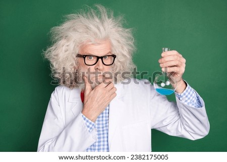Photo of thoughtful crazy minded mad scientist thinking hold glass with liquid isolated on green color background Royalty-Free Stock Photo #2382175005