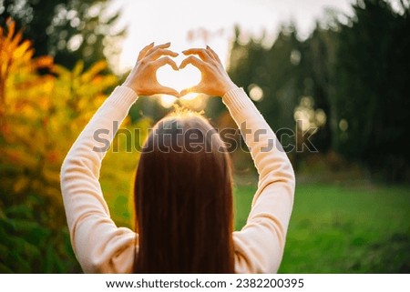A woman holding her hands in the shape of a heart. Heartwarming Gesture Formed by a Woman's Hands