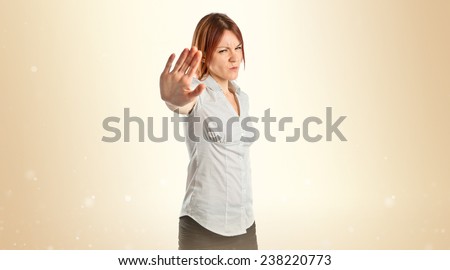 Pretty woman making stop sign over ocher background