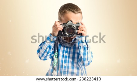 Boy photographing something over ocher background 