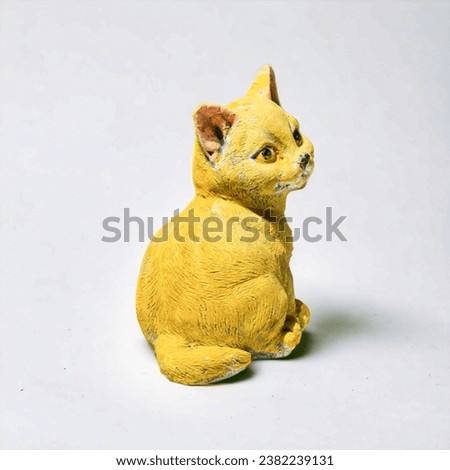 Cat figurine on a white background. The cat is yellow.