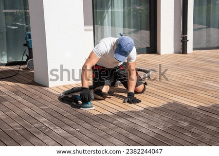 Renovation of weathered Ipe deck, restoration man cleaning silvery gray patina on the house patio terrace 