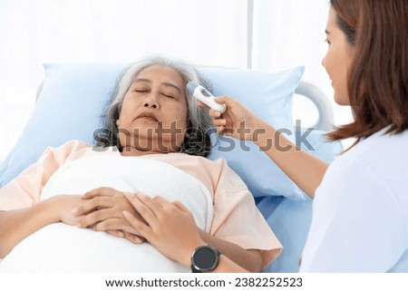 Elderly Asian patient admitted to hospital She has a cough and fever. Nurse uses a digital thermometer to take her temperature. Nurses care for patients in hospitals or clinics.