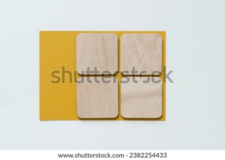 four wooden squares with rounded corners on a yellow card and blank paper