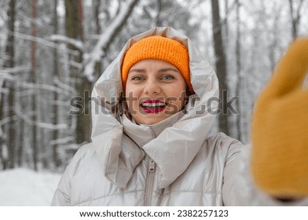 Young female tourist in warm clothes and yellow gloves making selfie, winter city, hiking at mountain forest. Successful hiker smiling at camera 