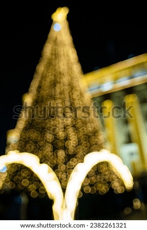 Abstract Christmas background with lights on a dark background. The silhouette of a Christmas tree is visible.