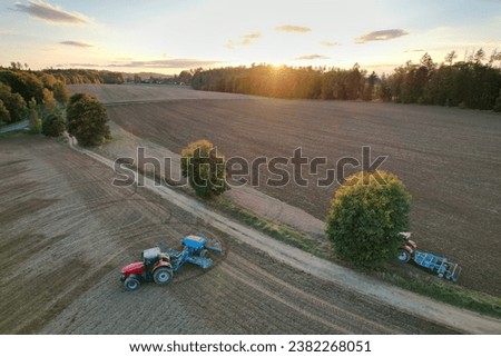 Farmer with tractor seeding-sowing crops at agricultural field. Plants, wheat.Soil loosening in a field with agricultural crops, aerial shot. The tractor processes the soil.drone view.Agricultural 