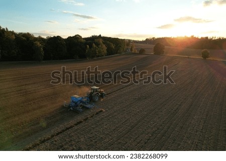 Farmer with tractor seeding-sowing crops at agricultural field. Plants, wheat.Soil loosening in a field with agricultural crops, aerial shot. The tractor processes the soil.drone view.Agricultural 