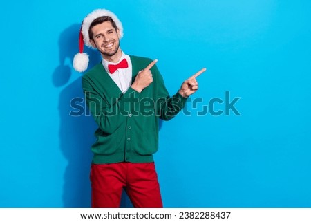 Photo of sweet funky guy dressed xmas green cardigan pointing two fingers empty space isolated blue color background