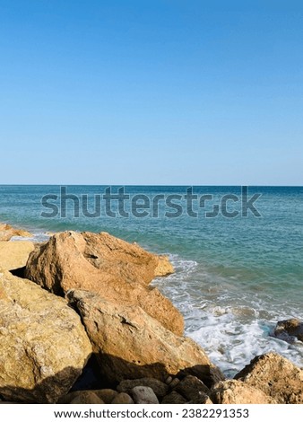 Rocky coast of the ocean, blue vivid sea, clear sky, rocks and stones