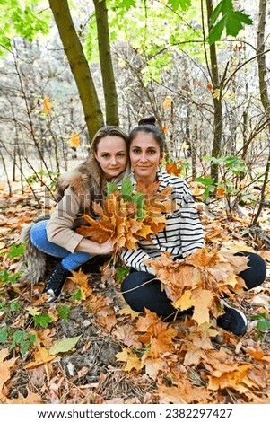Women at a barbecue in the autumn forest, taking pictures in the autumn leaves.