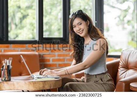 Portrait of Asian business female using laptop beautiful woman working on a computer in stylish Working Design in creative workplace.