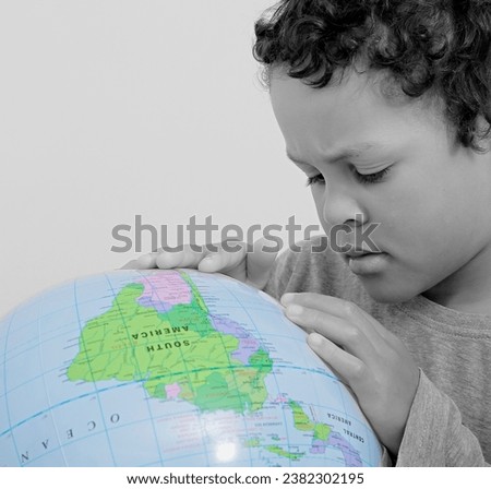 boy with globe looking at globe in school on grey background with people stock image stock photo