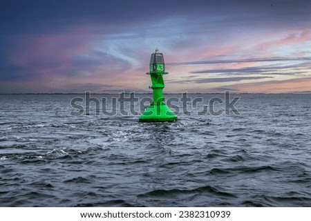 A buoy indicating the boundaries of a waterway. A bright green side buoy guiding ships in the North Sea.