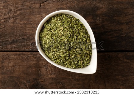 Dried lovage in bowl on retro wooden background. Top view  Royalty-Free Stock Photo #2382313215