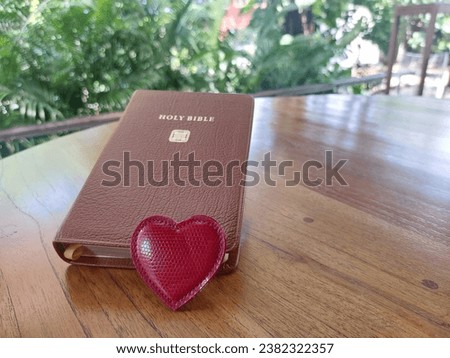 Red heart with Bible on table  at terrace in garden. Love reading bible, Study bible everyday. Faith hope Believe salvation concept. Christianity background