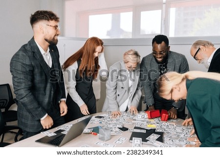 Happy successful multiethnic business team of mixed-aged diverse coworkers having fun, raise money from table, rejoicing from successful ending project. Diverse staff having party celebrating victory