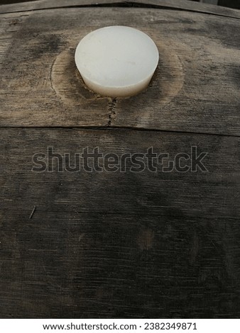 bung hole in wooden barrel with rubber bung cork in hole used for aging wine ales or spirits background  Royalty-Free Stock Photo #2382349871