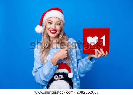 Photo portrait of lovely blonde young lady hold pointing like icon dressed penguin sweater x-mas hat isolated on blue color background