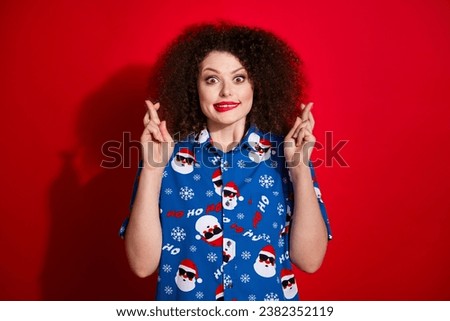 Photo portrait of attractive young woman crossed fingers excited dressed stylish blue x-mas print clothes isolated on red color background