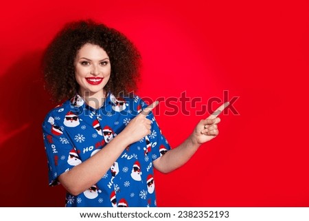 Photo portrait of attractive young woman pointing empty space dressed stylish blue x-mas print clothes isolated on red color background