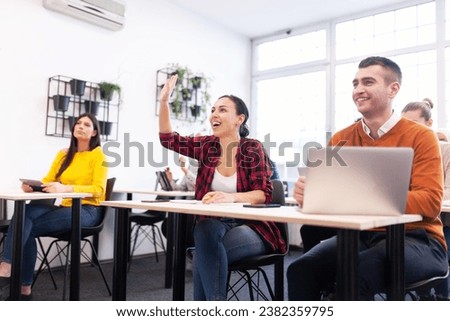 Multi ethnic students listening to a lecturer in a classroom. Smart young people rasing hands during class. Royalty-Free Stock Photo #2382359795