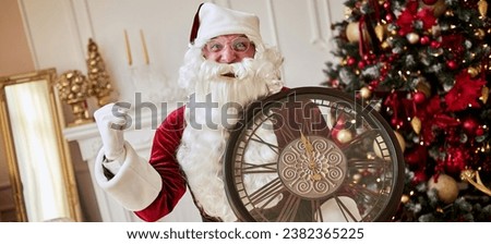 Five minutes to New year or Christmas midnight. Happy Santa Claus with clock showing winner sign