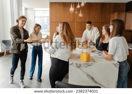 Positive friends celebrating birthday enjoying corporate party at home. Group people young men women colleagues eating drinks and snacks at dinning table