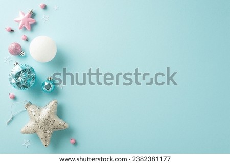 A sophisticated winter holiday affair with trendy decorations. Overhead shot of baubles, gleaming star, pink mistletoe berries on pastel blue backdrop, offering room for text or promotion