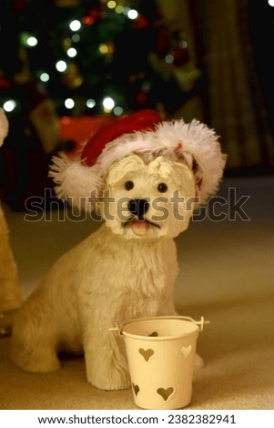 A Westie dog doll wearing Father Christmas hat on bokeh lights blurred background. Decorating on Christmas holidays.