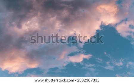 Scenic rose golden glowing big cloud highlighted by Sunset. Close up panoramic aerial photo of deep blue sky with puffy clouds