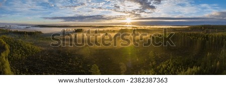 Scenic drone panorama photo of very foggy sunrise over forest, landscape in North Sweden, golden sun light beams and shadows. Beautiful northern Sweden, Vasterbotten, Umea, lens flare Royalty-Free Stock Photo #2382387363