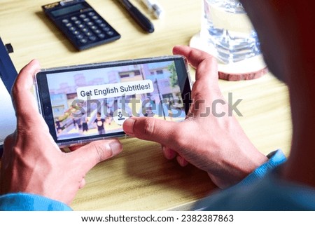 Man downloading English subtitles for the ongoing foreign language video. Selective focus.  Royalty-Free Stock Photo #2382387863
