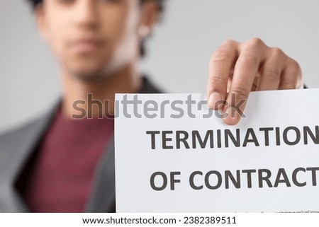 Amidst muted emotions on a blurred face, the starkness of a termination notice resonates, emphasizing the gravity of the situation Royalty-Free Stock Photo #2382389511