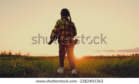 Happy kid Girl Runs Through Green Grass at Sunset. Children dream Happy concept. Joyful little girl runs in spring park. Kid is running across field. Child playing in nature. Happy family. Kid dream Royalty-Free Stock Photo #2382401363