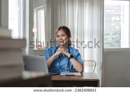 young asian lady doctor in white medical uniform with stethoscope using computer laptop talking video conference call with patient at desk in health clinic or hospital.