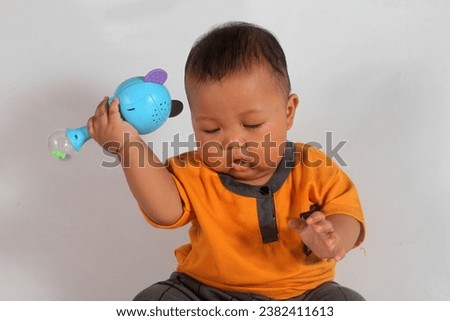 Adorable six month old chubby baby boy learning to sit and play on white background Royalty-Free Stock Photo #2382411613