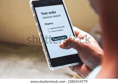 Advantage of click and collect or in-store pickup service concept on smartphone display. Man choosing click and collect option for his purchase. Selective focus.