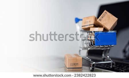 Shopping cart and product boxes on laptop computer on white background and copy space. online shopping marketplace platform website E-commerce technology, shipping, logistics and online payment concep