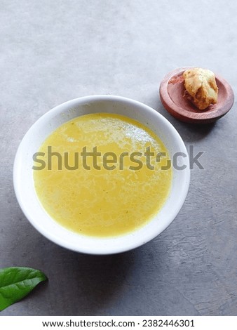 Homemade chicken stock in a bowl on a gray background. soup. chicken gravy. yellow sauce. ingredients. delicious. vertical shot