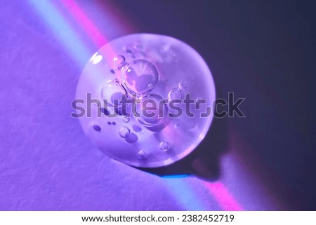 A drop of serum under ultraviolet light. Royalty-Free Stock Photo #2382452719
