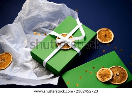 Green gift box with white paper and oranges.