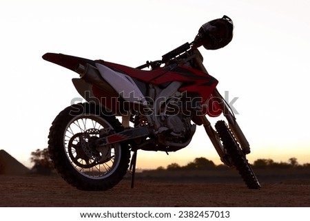 Dirt, bike and sunset in desert for action danger competition, fast race or speed training. Off road, motorcycle and helmet outdoor for fearless brave adventure, adrenaline or extreme sport transport